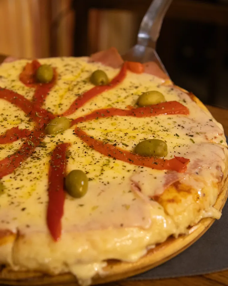 Pizza a la piedra con jamón, morrón y aceitunas