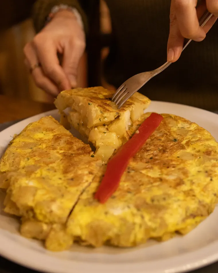 Tortilla española cortándose en la mesa, con morrón